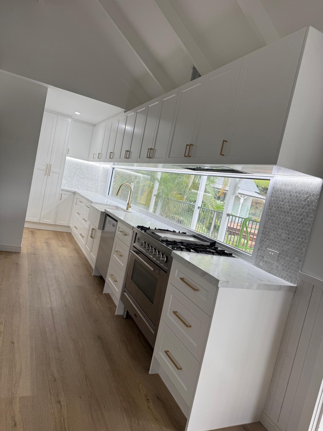 White shaker kitchen with marble benchtops and a window splashback, built and installed by Quality Cabinets