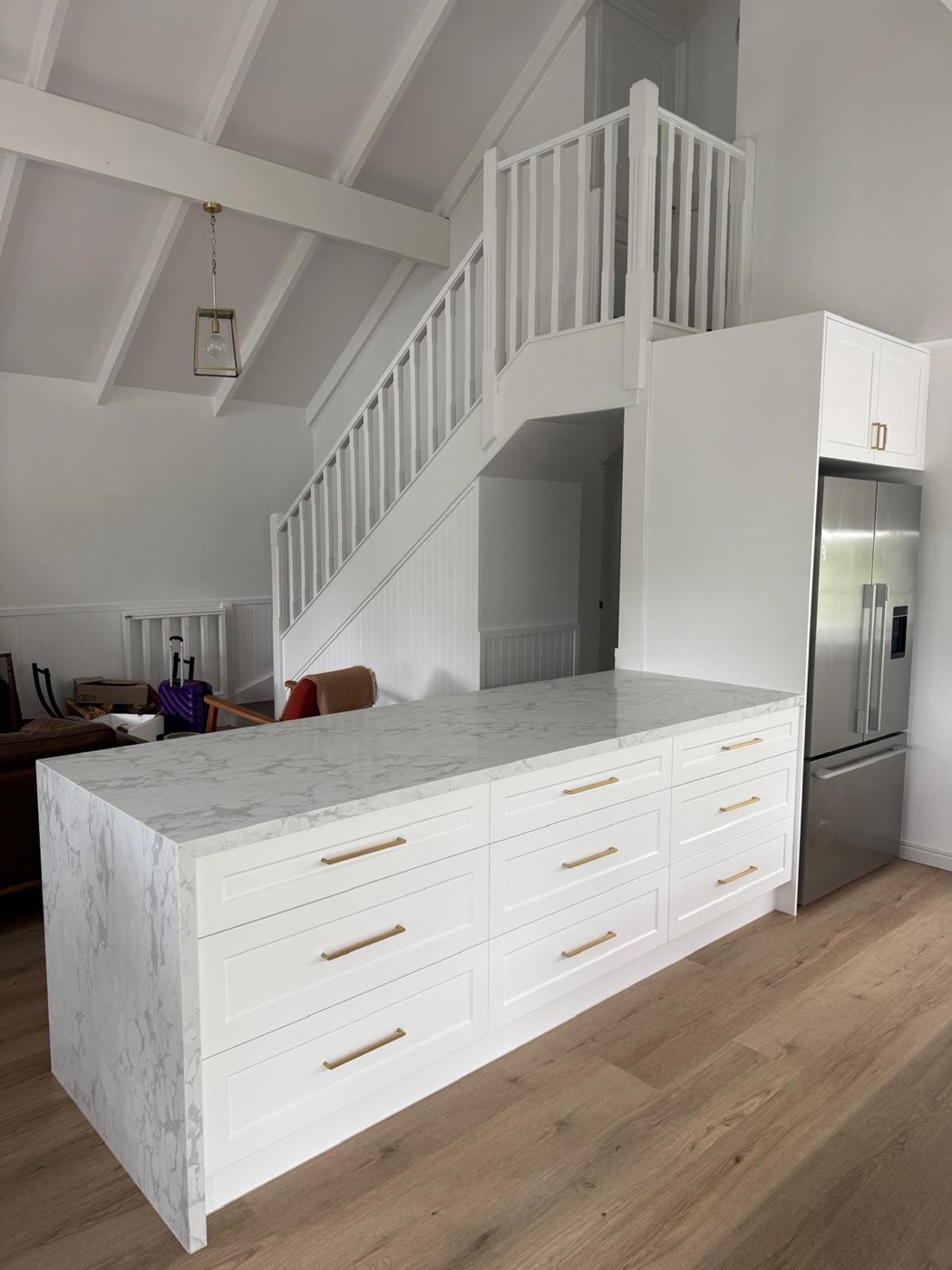 Marble-topped island with white shaker drawer fronts and brass handles