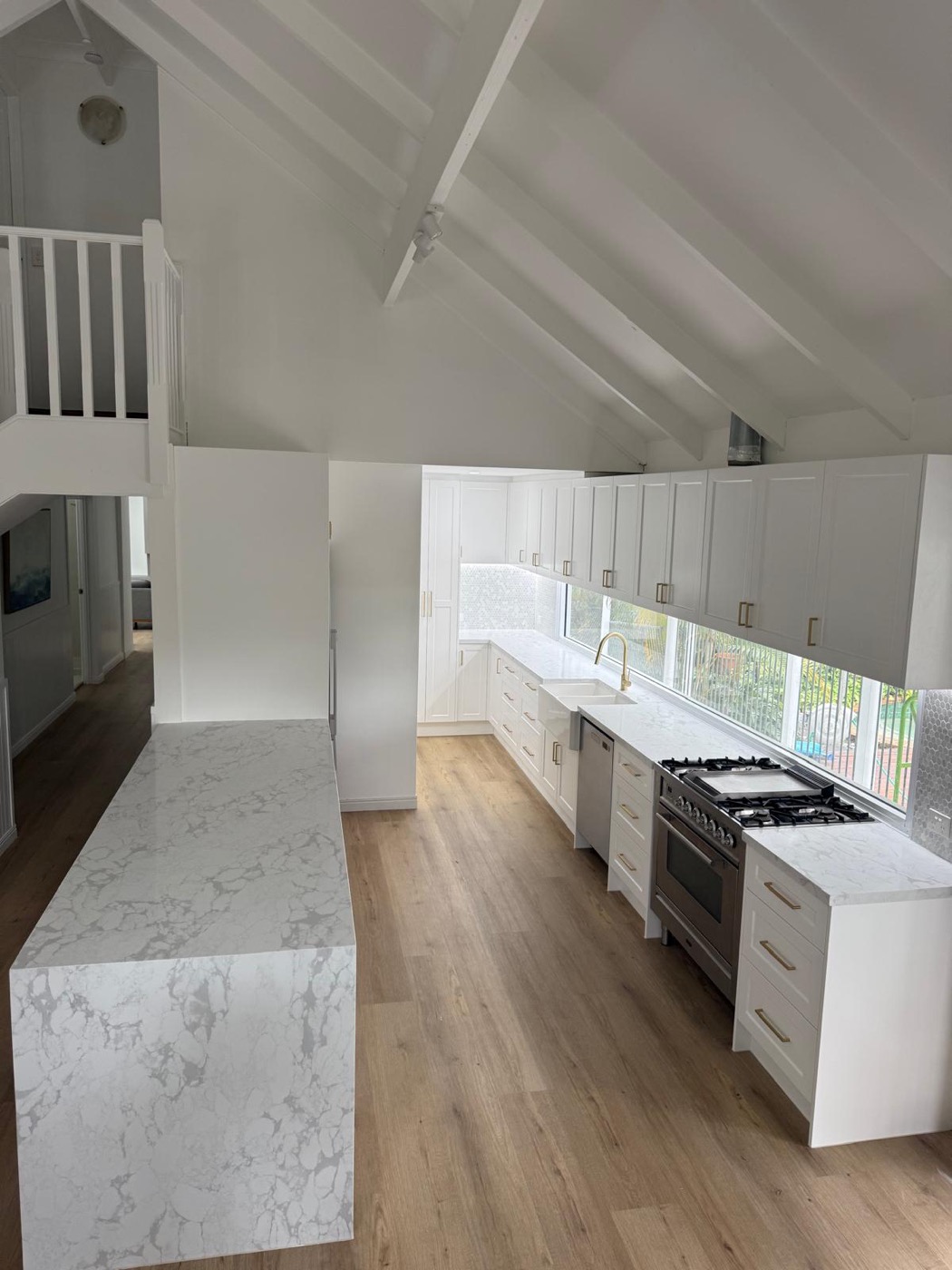 Long galley kitchen under a raked ceiling with a marble island run