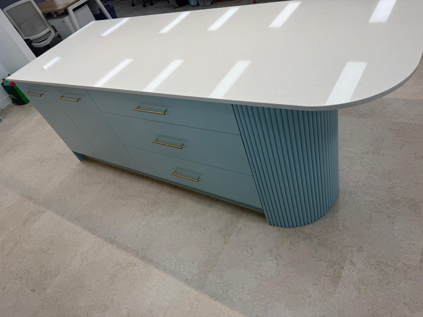 Close view of a fluted blue island base with brass pulls and a stone top