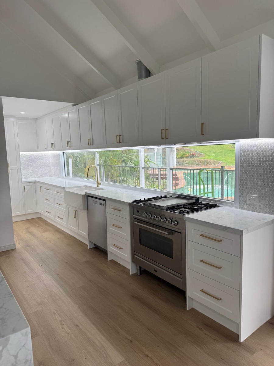 Custom white shaker kitchen with gas cooktop and window splashback, built by Quality Cabinets