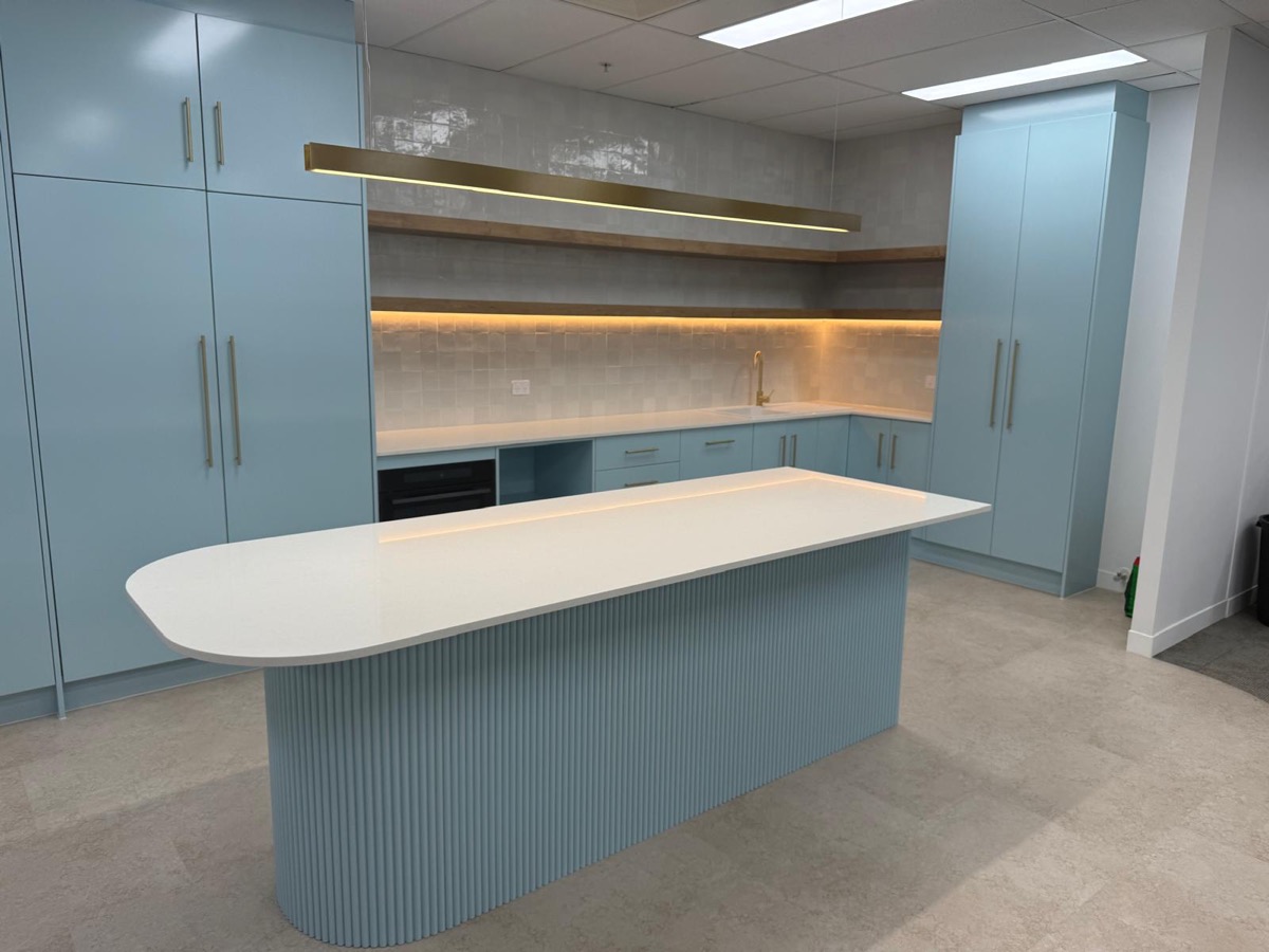 Curved fluted kitchen island with white stone benchtop, built by Quality Cabinets
